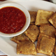Plate of toasted ravioli with side of red sauce